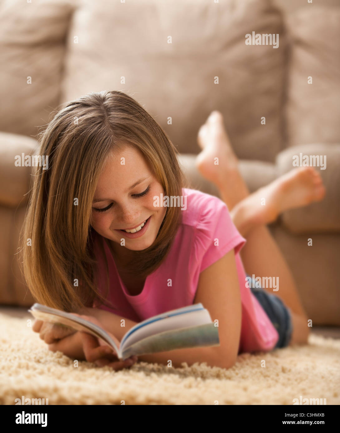 Mädchen (10-11) liegen auf Teppich, Buch lesen Stockfoto