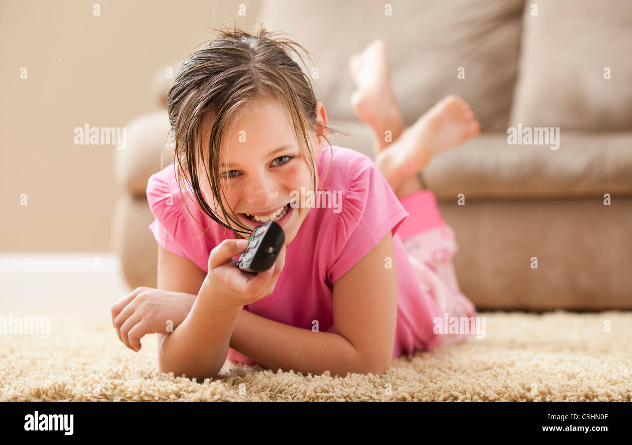 Porträt eines Mädchens (10-11) auf Boden mit Fernbedienung Stockfoto