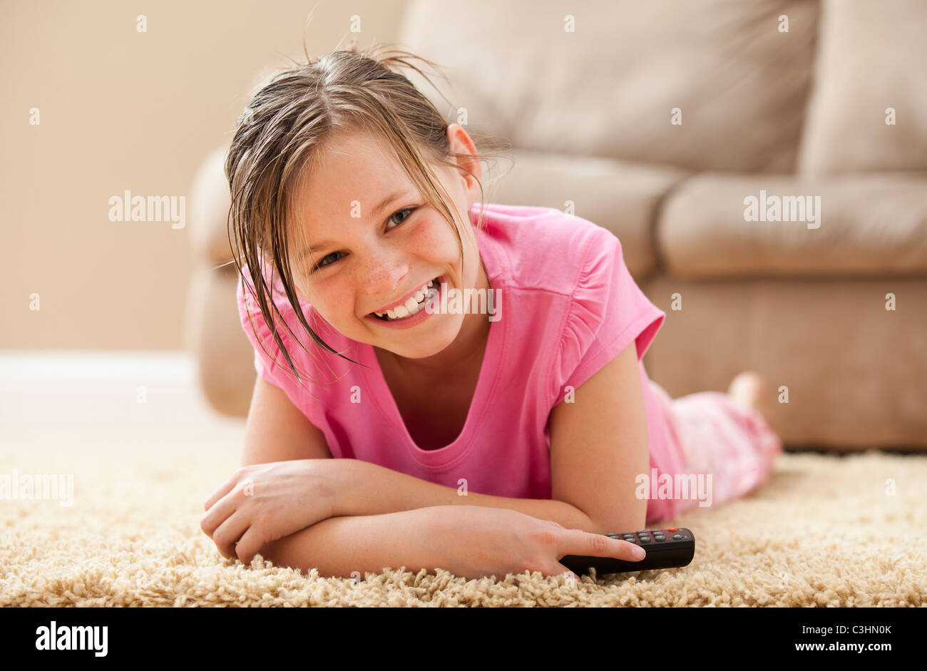 Porträt eines Mädchens (10-11) auf Boden mit Fernbedienung Stockfoto