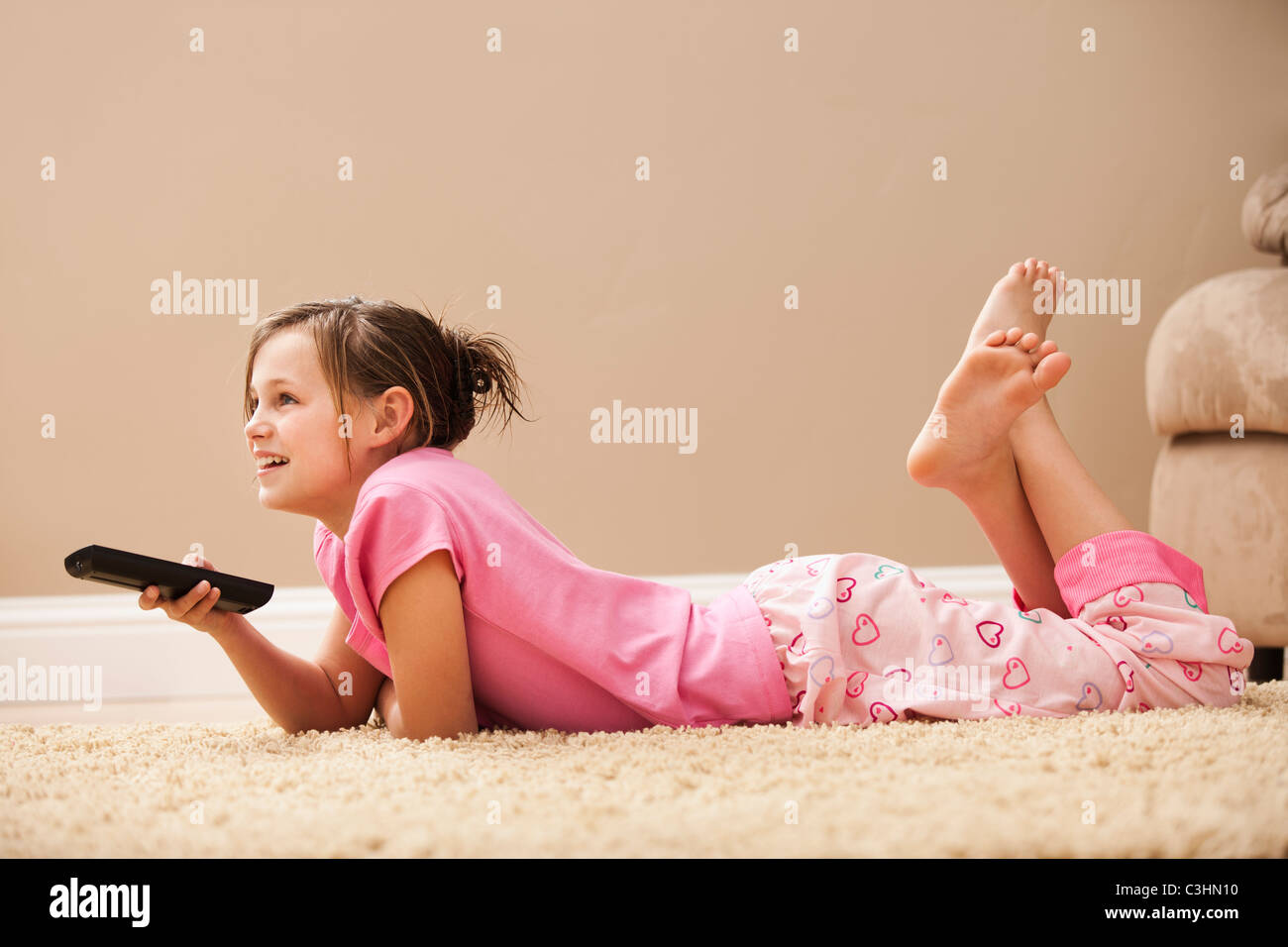 Mädchen (10-11) auf Boden mit Fernbedienung Stockfoto