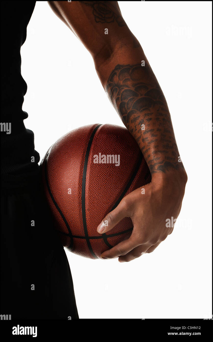 Mittelteil der tätowierte Mann hooding basketball Stockfoto