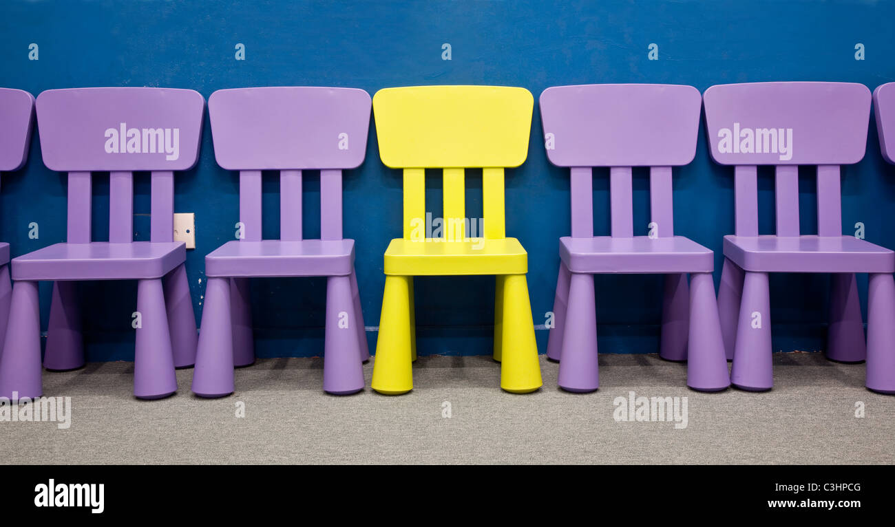 Kinderstühle - gelb gefärbten eine in der Mitte mehrere lila farbigen Stühle für Kinder Stockfoto