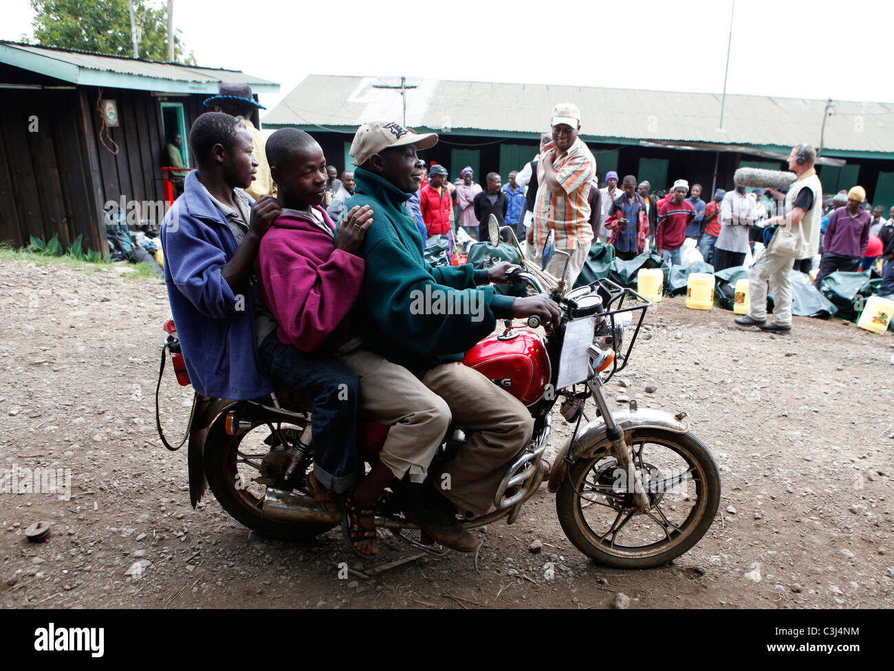 Drei Männer sitzen auf einem Motorrad fahren durch lokale Helfer wartet auf den Start der Kilimanjaro-Besteigung, Marangu-Route Stockfoto