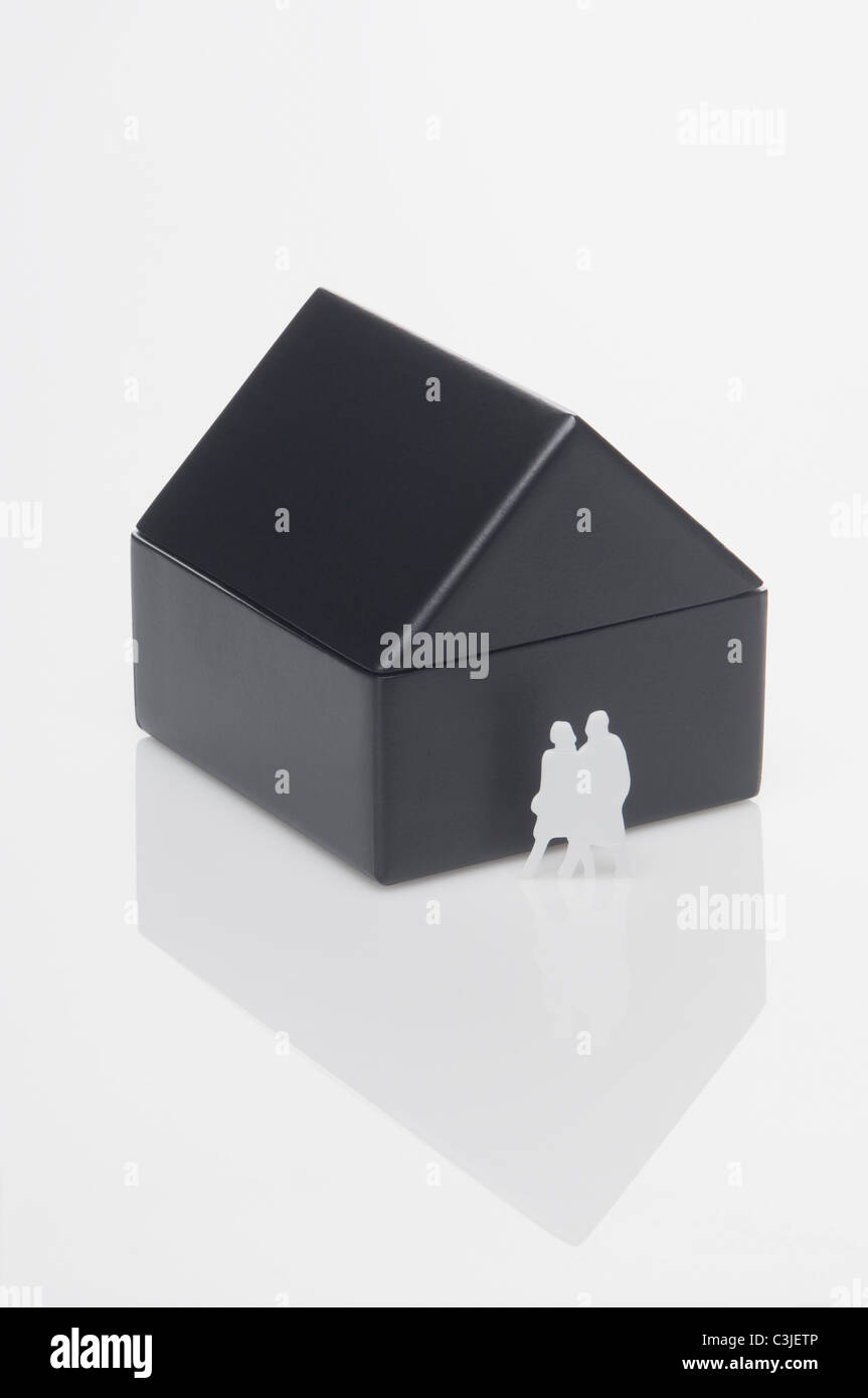 Figuren vor Miniatur-Haus auf Whtie Hintergrund Stockfoto