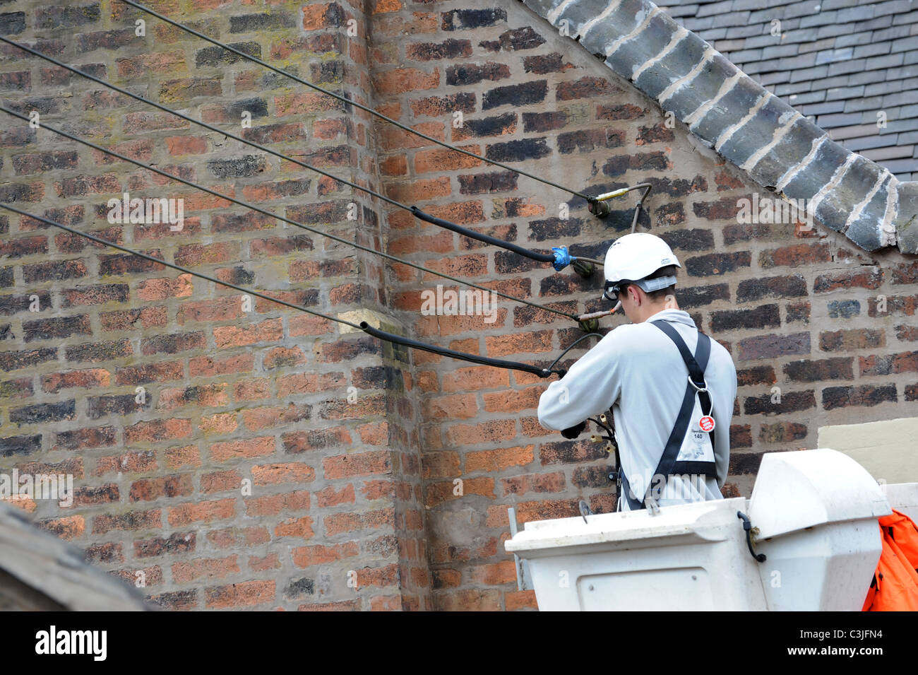 Elektrische Conractor Repalcing alte externe Kabel auf alten Haus UK Stockfoto