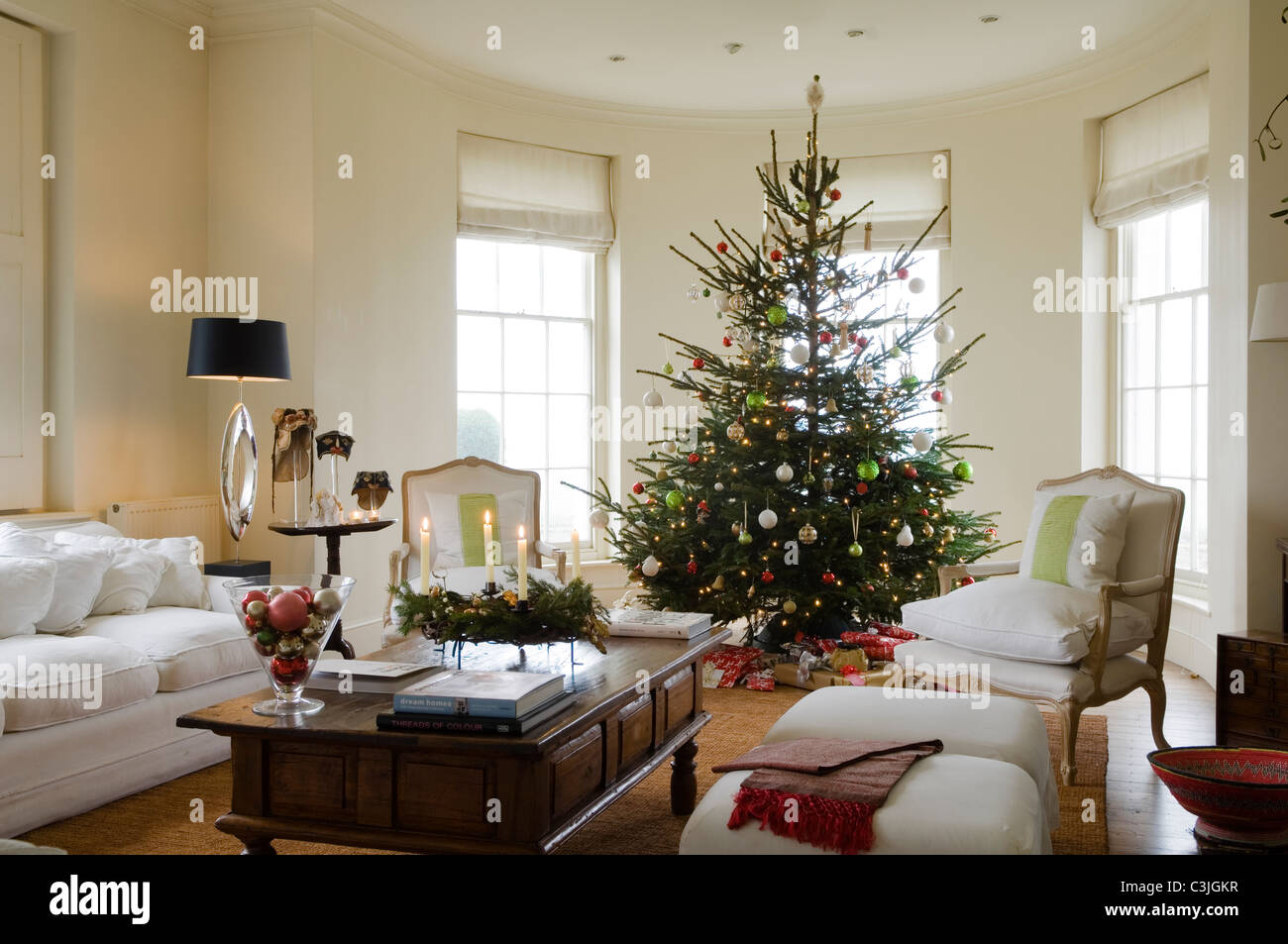 Geschmückter Weihnachtsbaum mit Kugeln im regency Wohnzimmer mit Sesseln und Kerzen Stockfoto