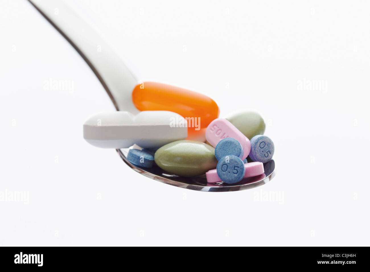Gemischte Tabletten in Löffel vor weißem Hintergrund Stockfoto