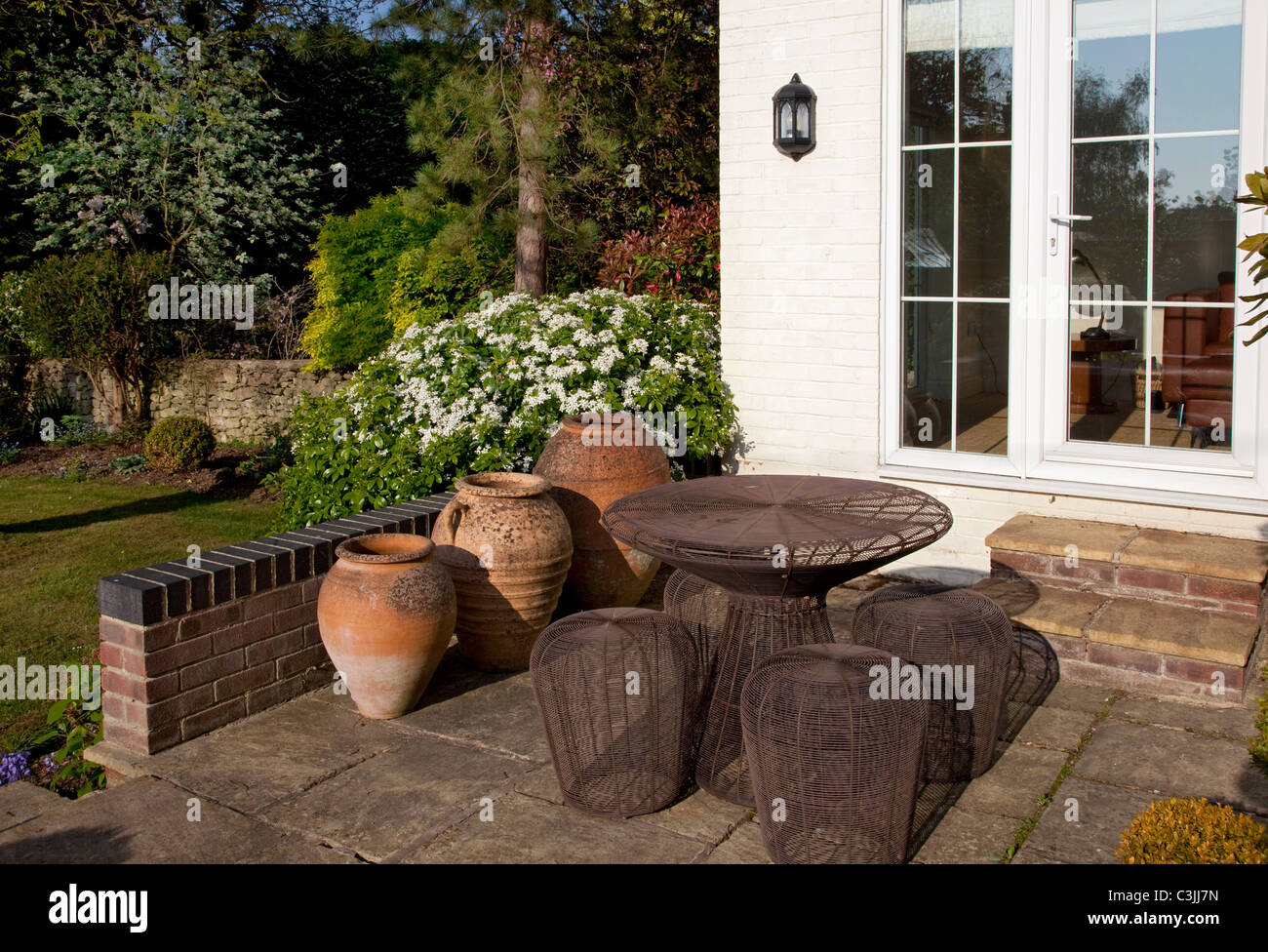 Stein Terrasse im englischen Garten mit Terrakotta-Töpfe und zeitgenössische Metall-Tisch und Stühlen Stockfoto
