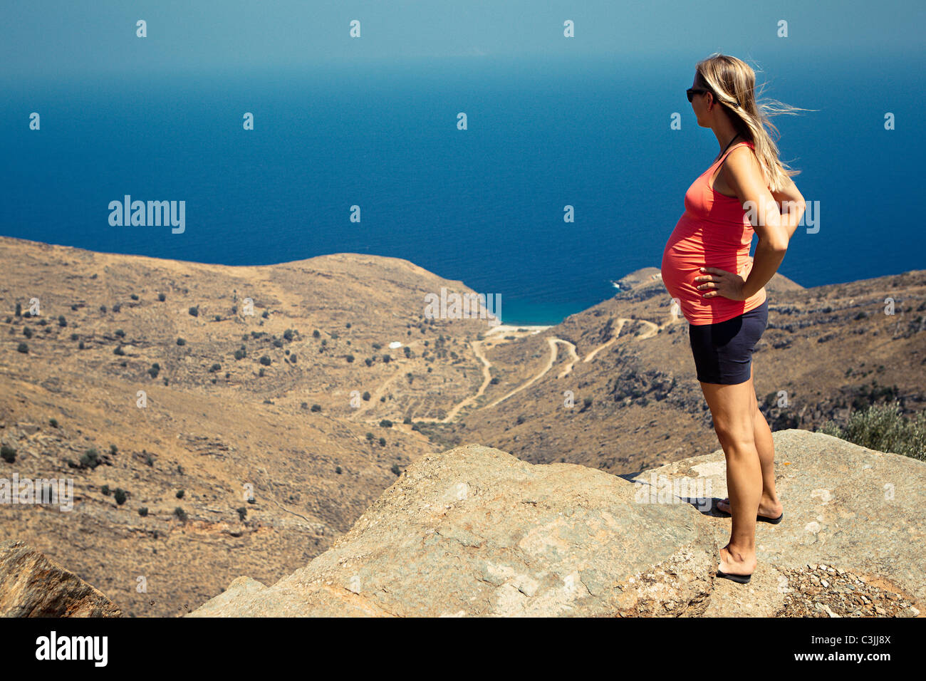 Schwangere Frau auf Anhöhe, Meer im Hintergrund Stockfoto