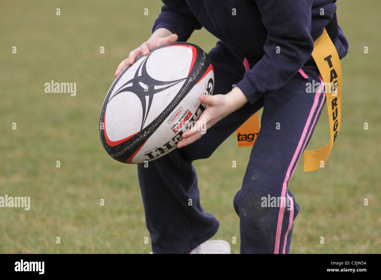 Junges Kind läuft mit einem Rugby-Ball Tag Rugby zu spielen Stockfoto