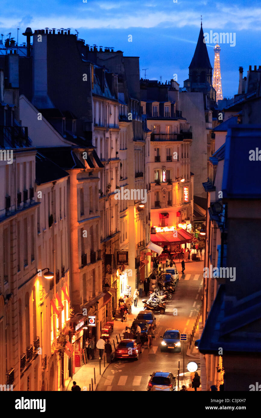 Eine beleuchtete Rue Saint-André des Arts bei Nacht mit dem Eiffelturm im Hintergrund, Paris Stockfoto
