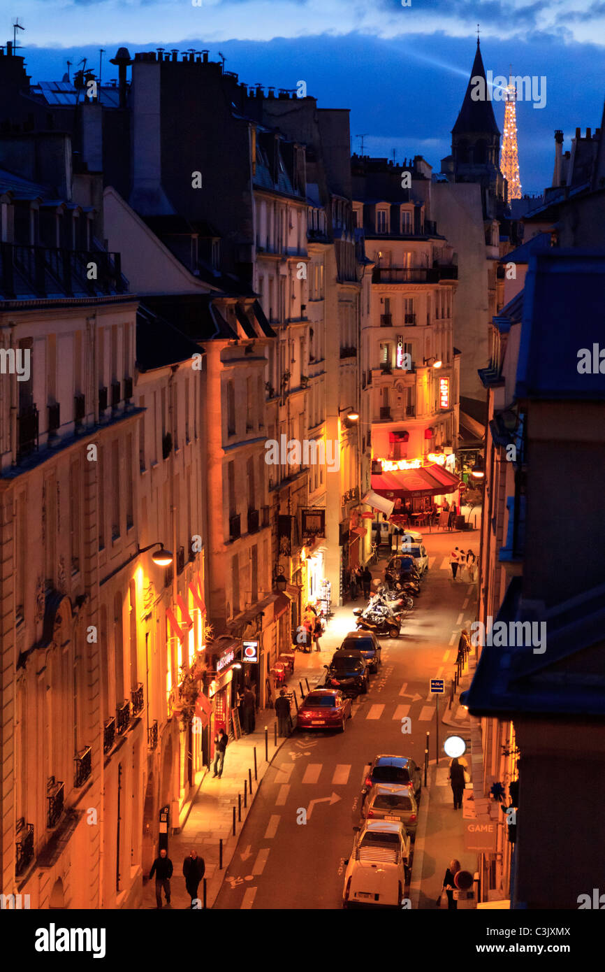 Eine beleuchtete Rue Saint-André des Arts bei Nacht mit dem Eiffelturm im Hintergrund, Paris Stockfoto