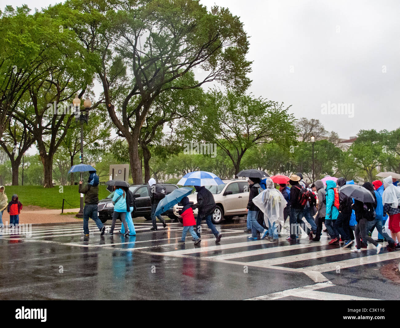 Mit Regenjacken und Schirme, folgen Sie Touristen eine Anleitung an einem regnerischen Tag auf der National Mall in Washington, D.C. Stockfoto