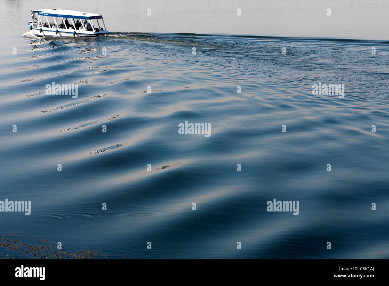 Ein Nil Wasser Taxi oben links Schuss verlassen großen tiefblauen Zuge, in ruhigem Wasser hinter, Ägypten, Afrika Stockfoto