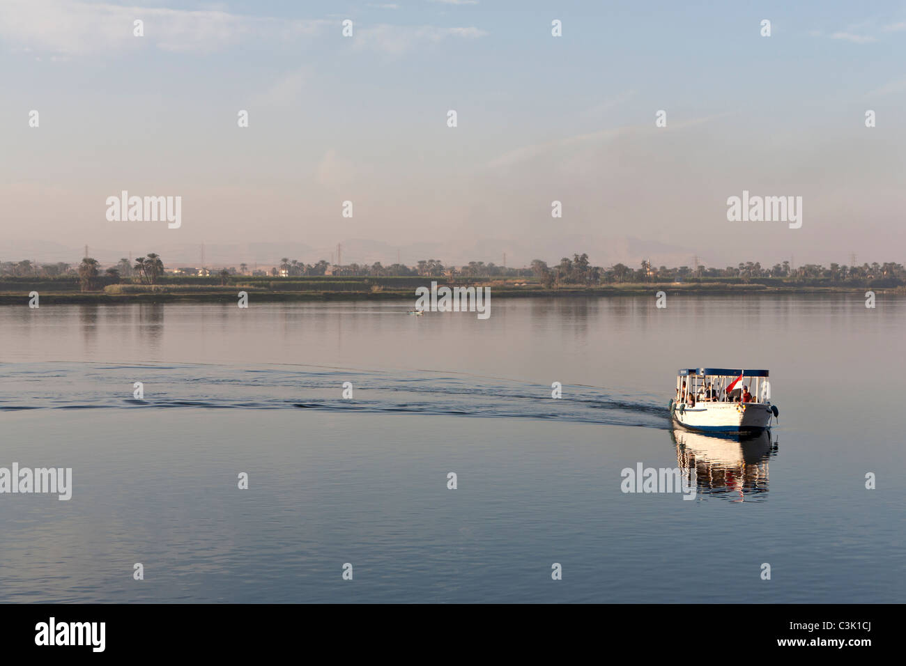 Ein Nil Wasser Taxi verlassen Gefolge, perfekt reflektiert, mit große Wasserfläche offen ruhig hinter Ägypten gebogen Stockfoto