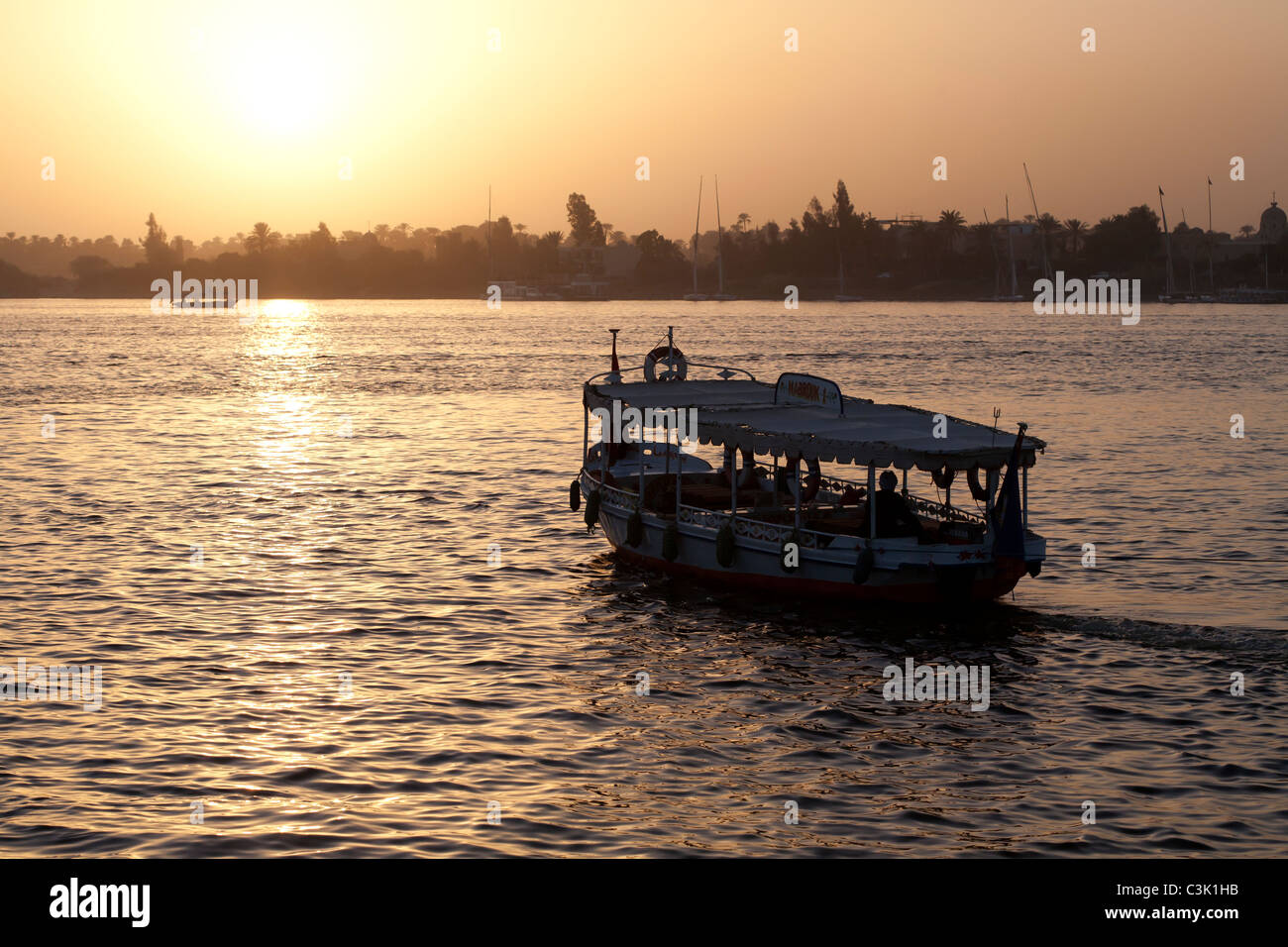 Ein Nil-Wasser-Taxi zum Westjordanland Luxor in der orangefarbenen Schein der untergehenden Sonne über Segeln Stockfoto