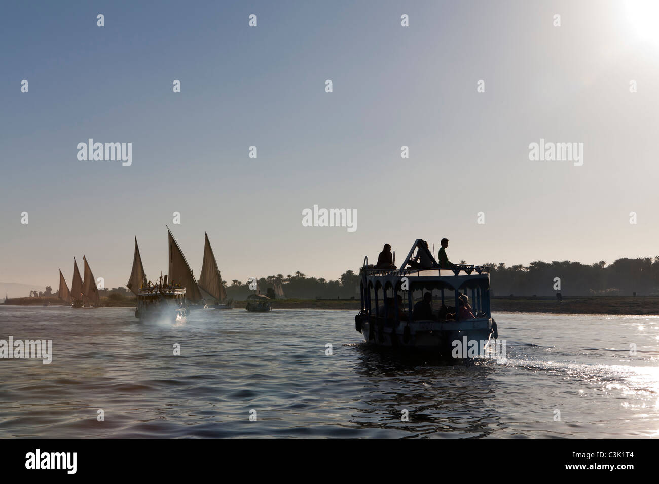 Im Anschluss an eine Nilwasser Wasser Taxi und mehrere Feluken Überschrift in den Sonnenuntergang auf den glitzernden Fluss, Ägypten, Afrika Stockfoto