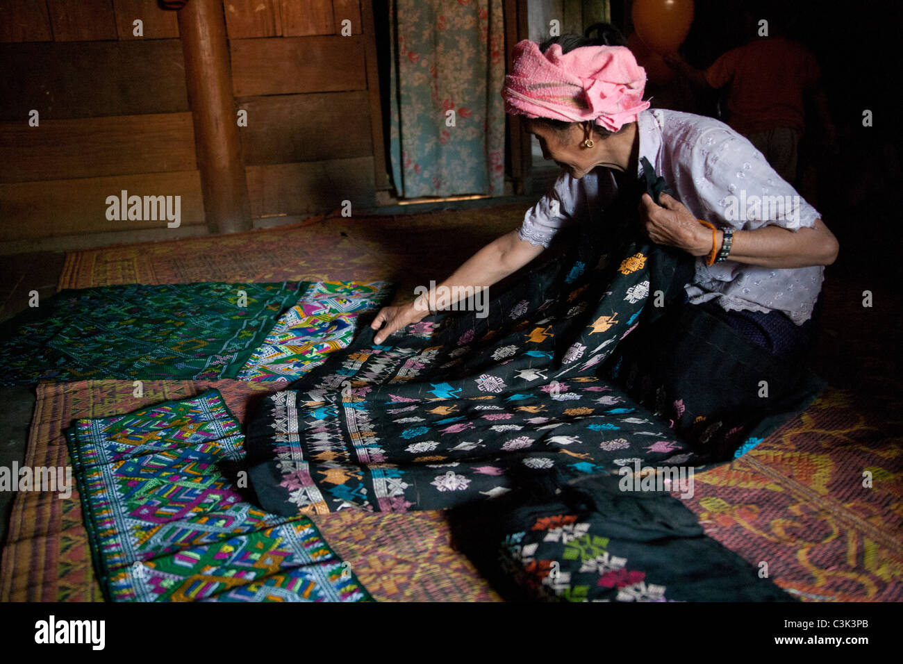 Eine Frau breitet ihr gewebte Ware für den Verkauf auf einer Hütte Stock, Xiangkhouang Provinz, Laos Stockfoto