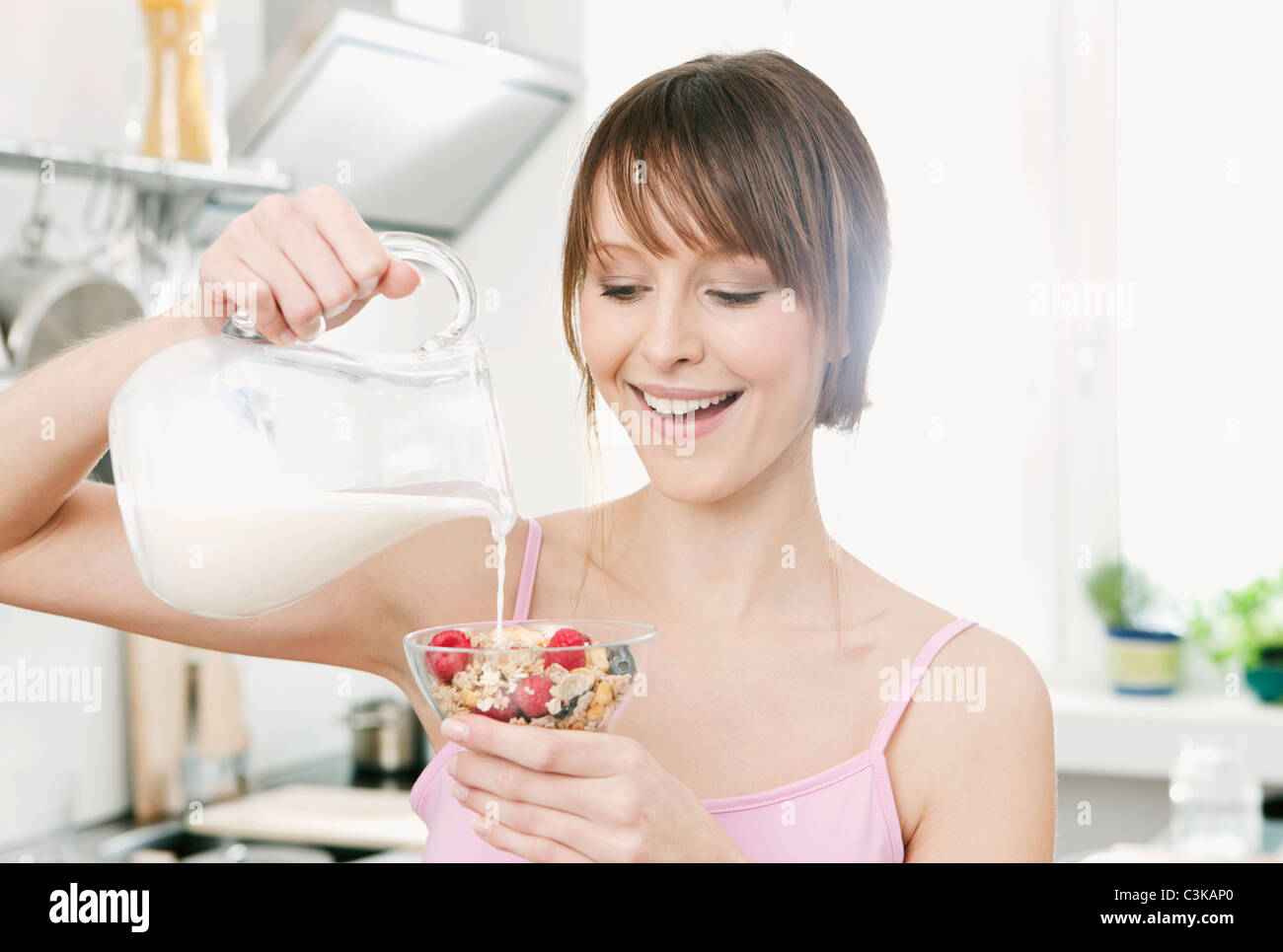 Deutschland, Köln, Frau Gießen Milch auf Früchte-Müsli Stockfoto