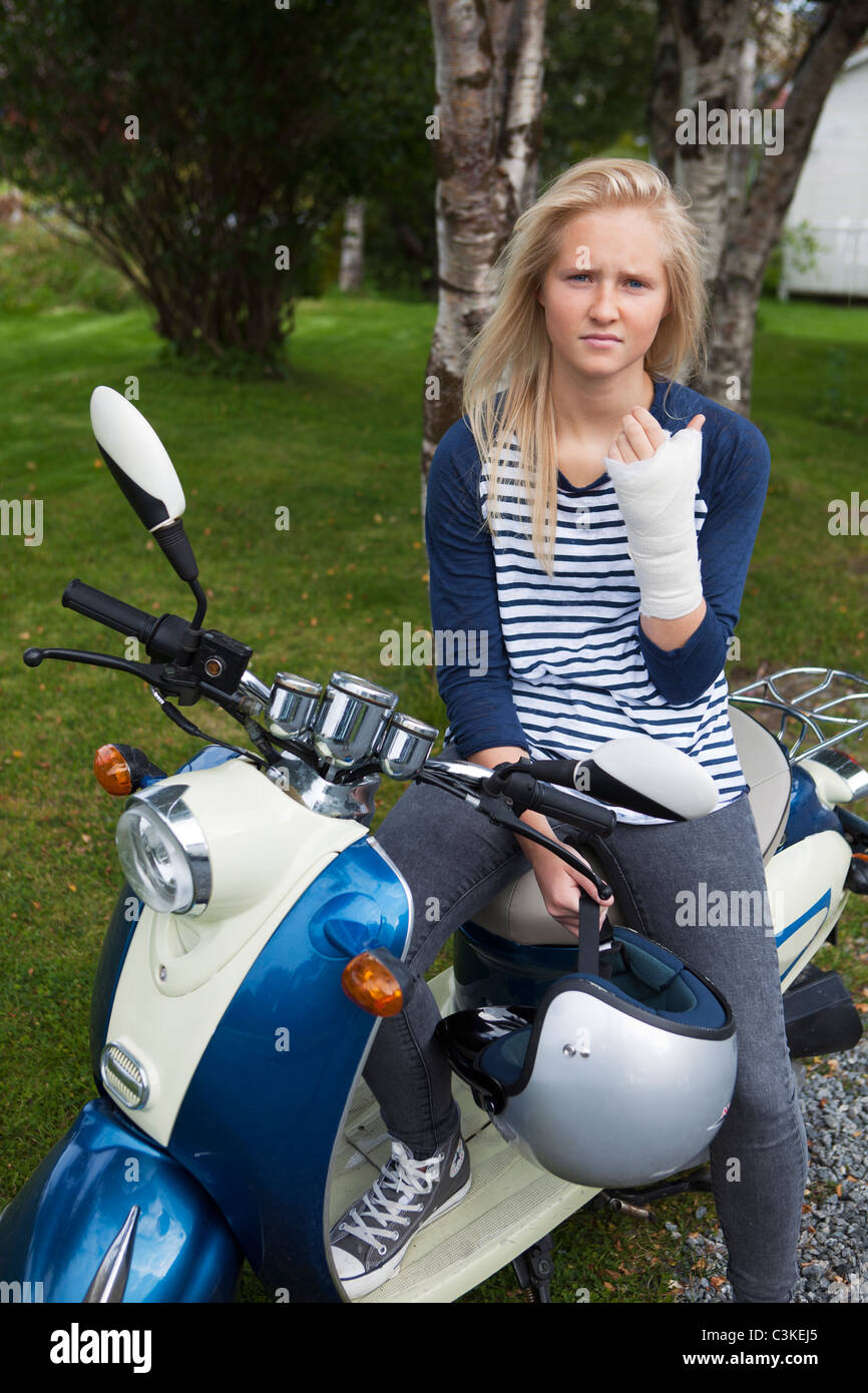 Teenager-Mädchen mit Bandage am Hand sitzen auf Roller Stockfoto