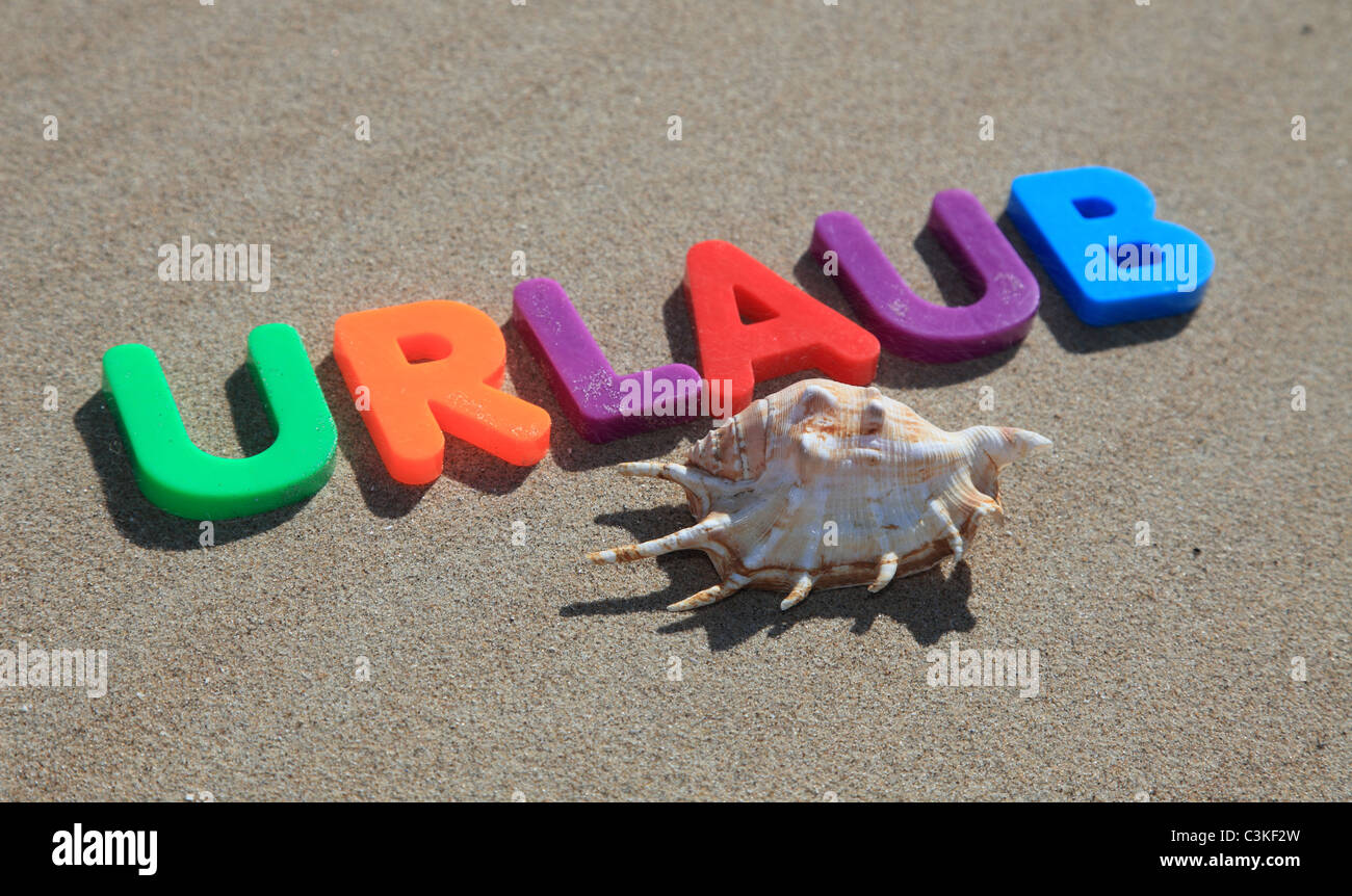 Der Begriff Urlaub in bunten Buchstaben auf dem Sand geschrieben. Stockfoto