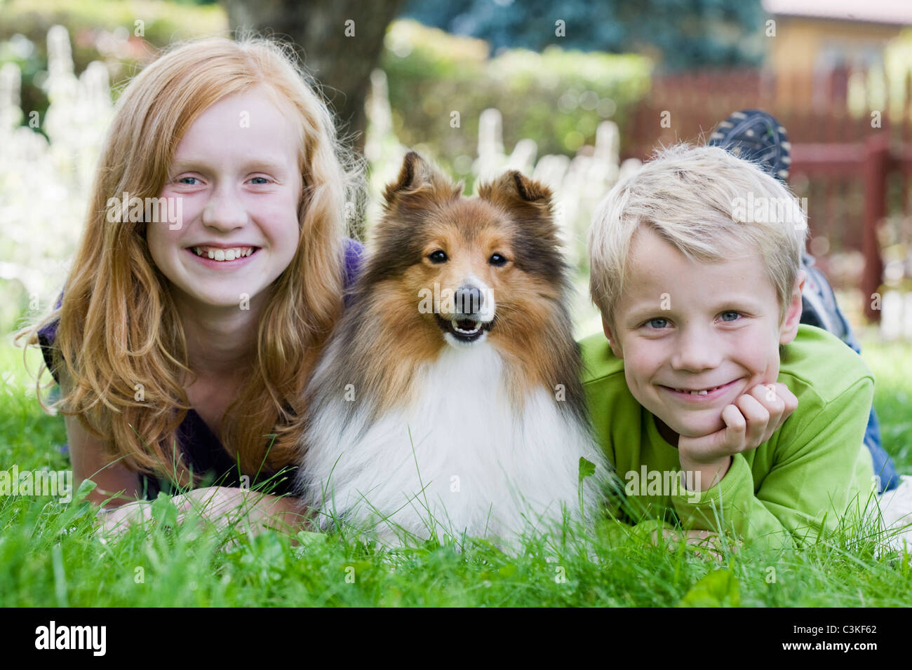 Jungen und Mädchen liegen auf dem Rasen mit Hund Stockfoto