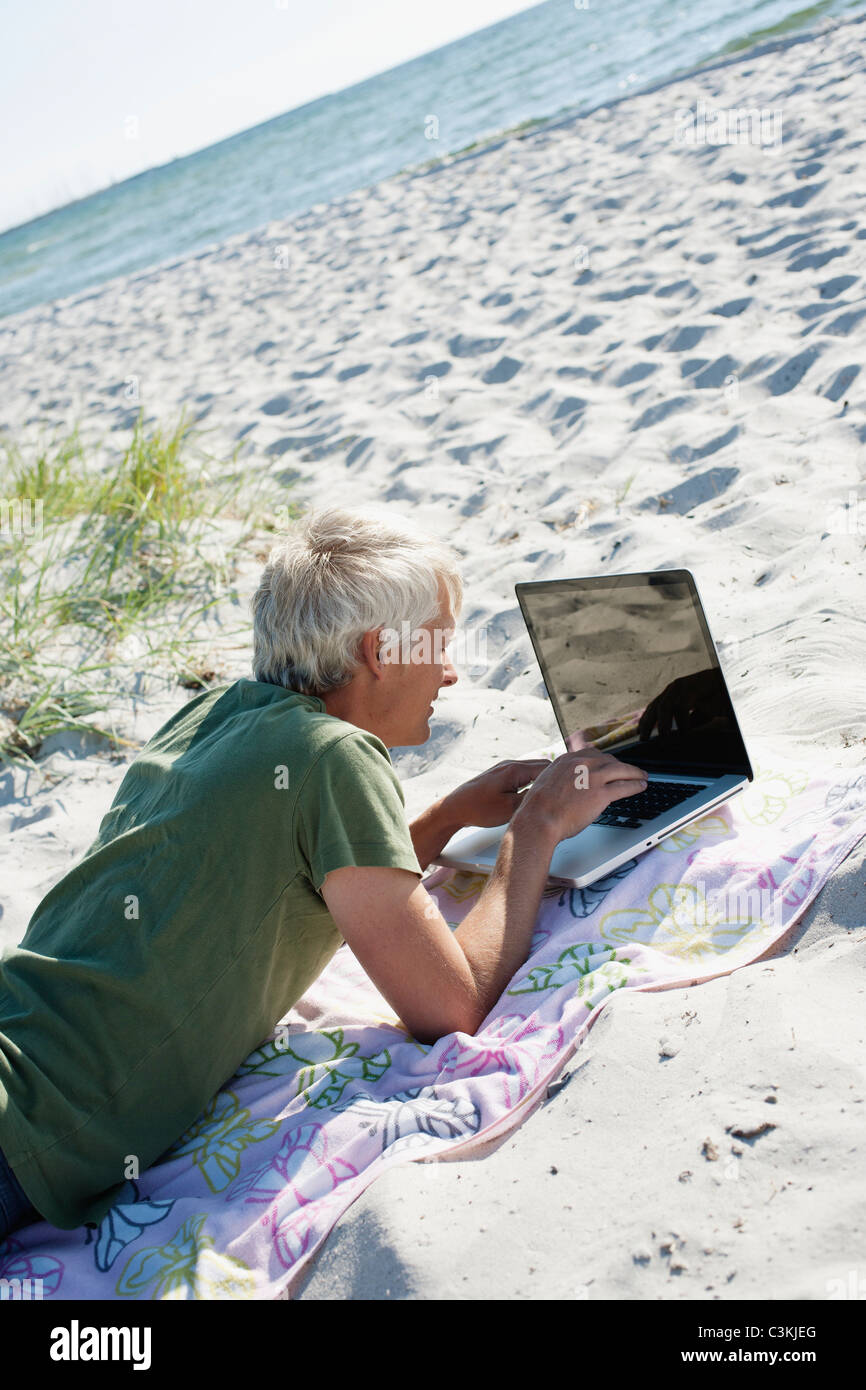 Mann mit Laptop am Strand Stockfoto