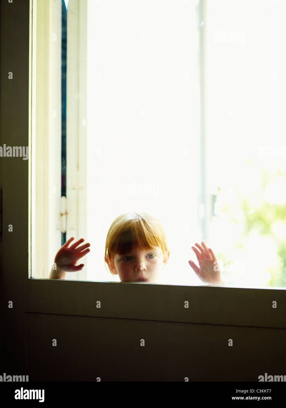 Rothaarige Mädchen Blick durch Fenster Stockfoto