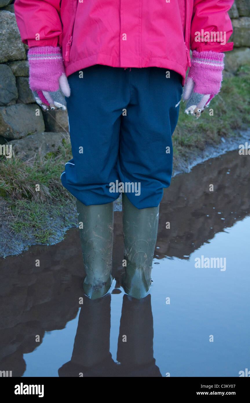 Kleines Kind (Mädchen) in grünen wellington Stiefeln (Gummistiefel) rosa  Regenmantel, Handschuhe & blaue Hose stehen in tief schlammigen Pfütze  (Beine & Körper) - England Stockfotografie - Alamy