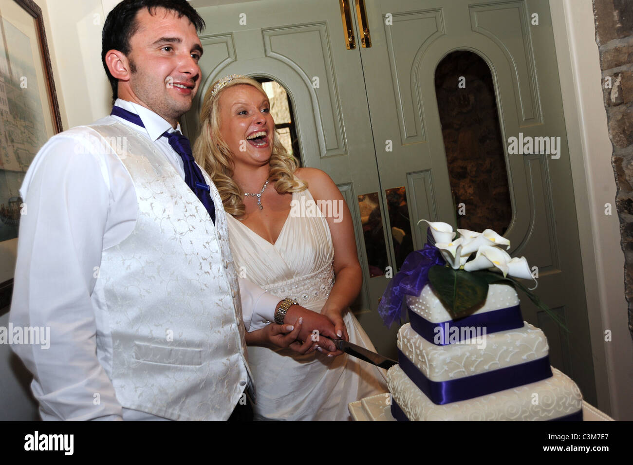 Ein frisch vermählte Paar schneiden Sie den Kuchen am Tag ihrer Hochzeit Stockfoto