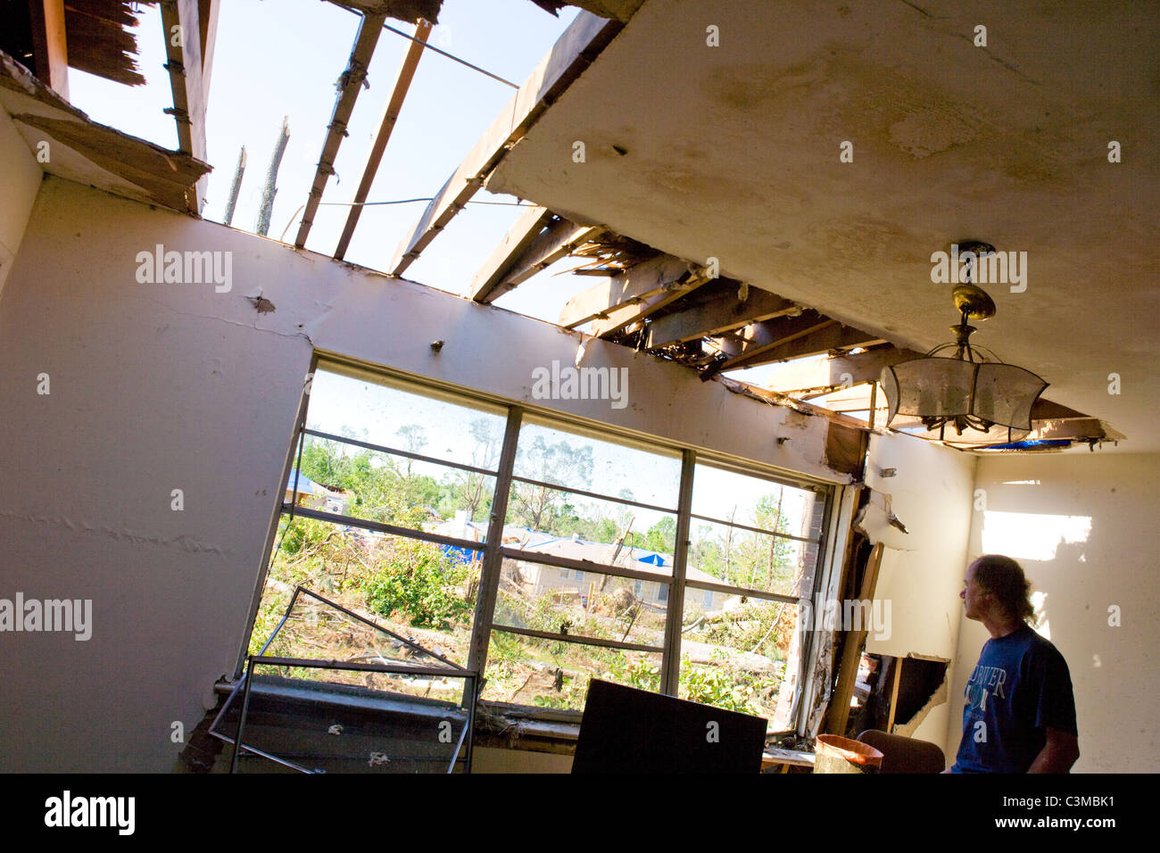 Mann sieht durch das Fenster seines beschädigten Hauses Tornado verwüstet hatte seiner Nachbarschaft in der Nähe von Tuscaloosa, Alabama, USA Stockfoto