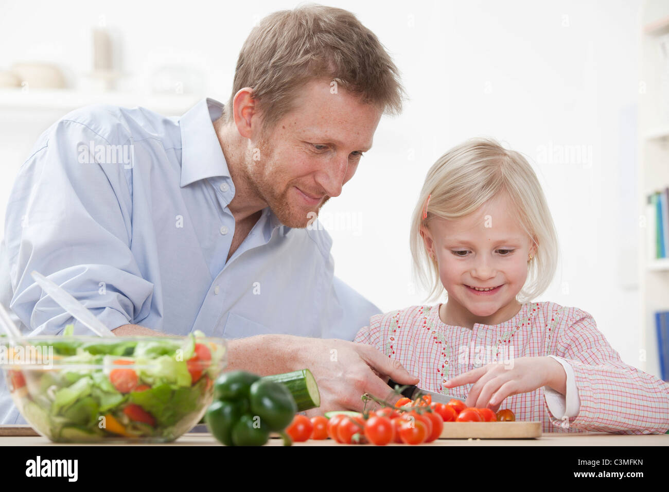 Deutschland, Bayern, München, Vater helfende Tochter zuzubereitende Salat, Lächeln Stockfoto
