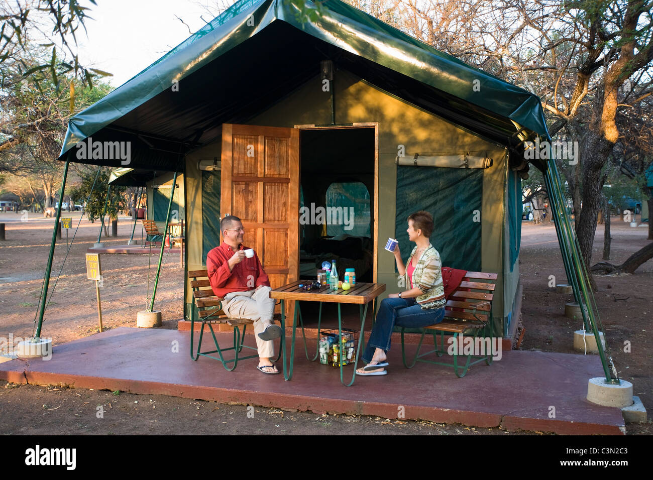 Südafrika, Pilanesberg National Park paar, Mann und Frau, frühstücken vor Safari-Zelt auf Campingplatz Stockfoto
