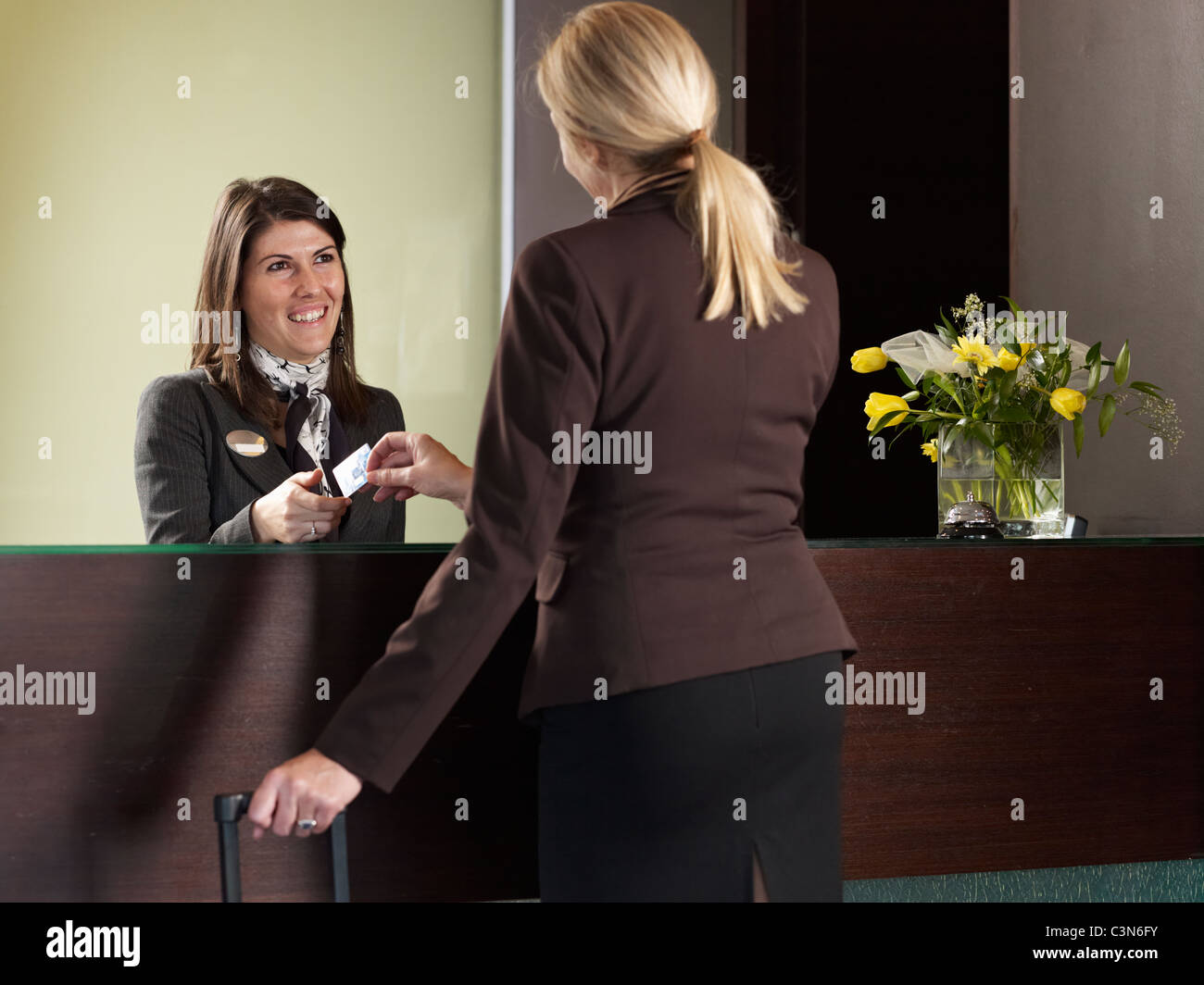 Geschäftsfrau, die Zahlung für ihr Hotelzimmer an der Rezeption Stockfoto