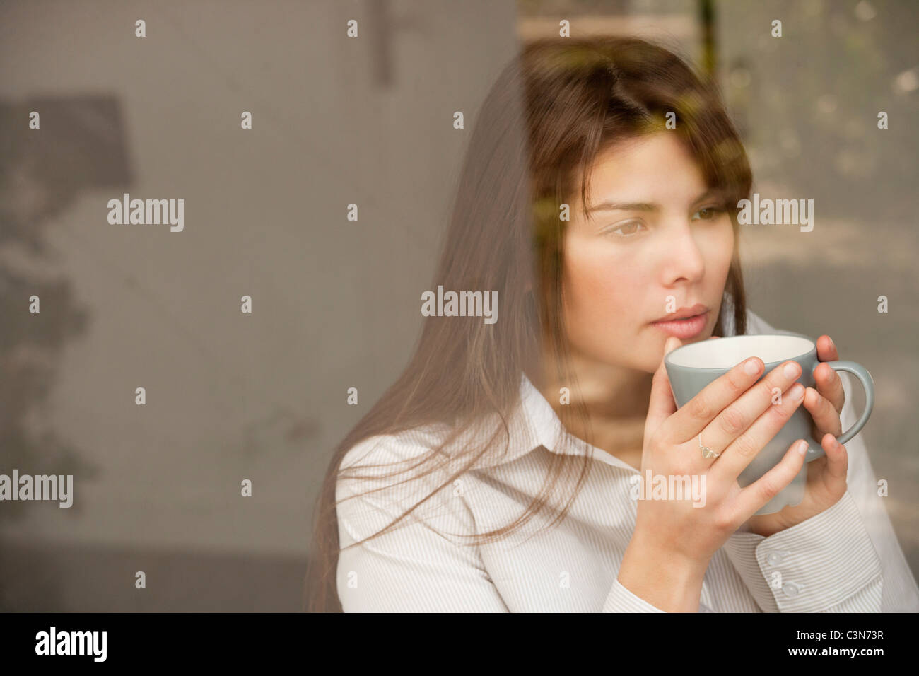 Frau trinkt Tee durch ein Fenster Stockfoto