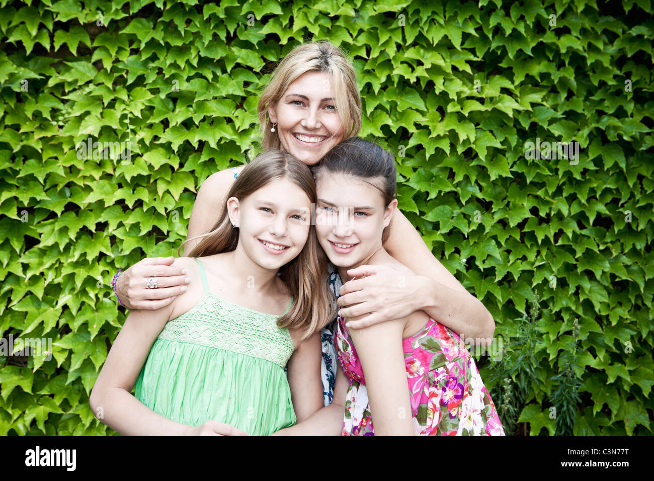 Mutter und Töchter vor bush Stockfoto