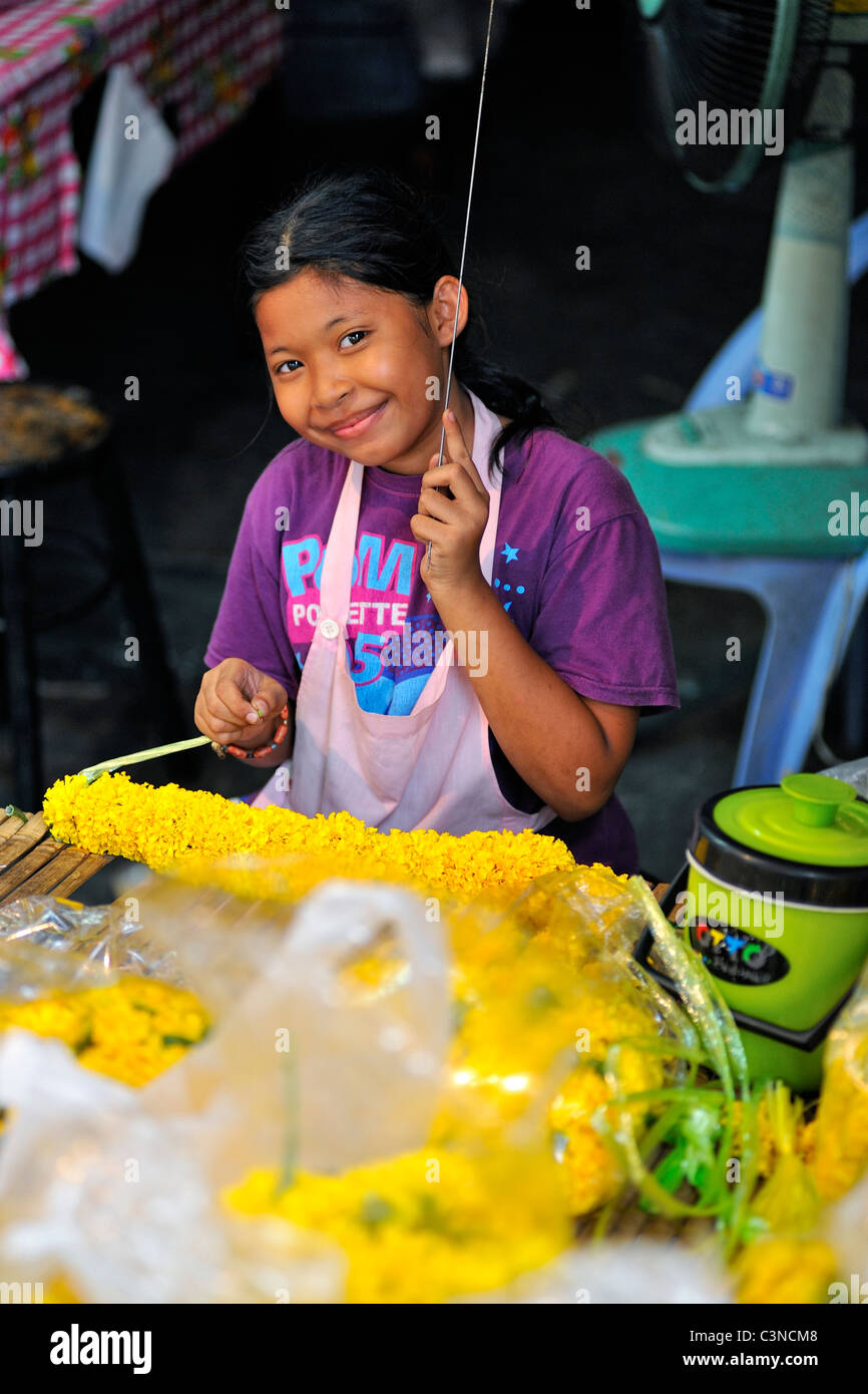 Thai-Mädchen machen schöne Girlanden aus Ringelblumeblume auf dem Blumenmarkt in Bangkok, Thailand Stockfoto