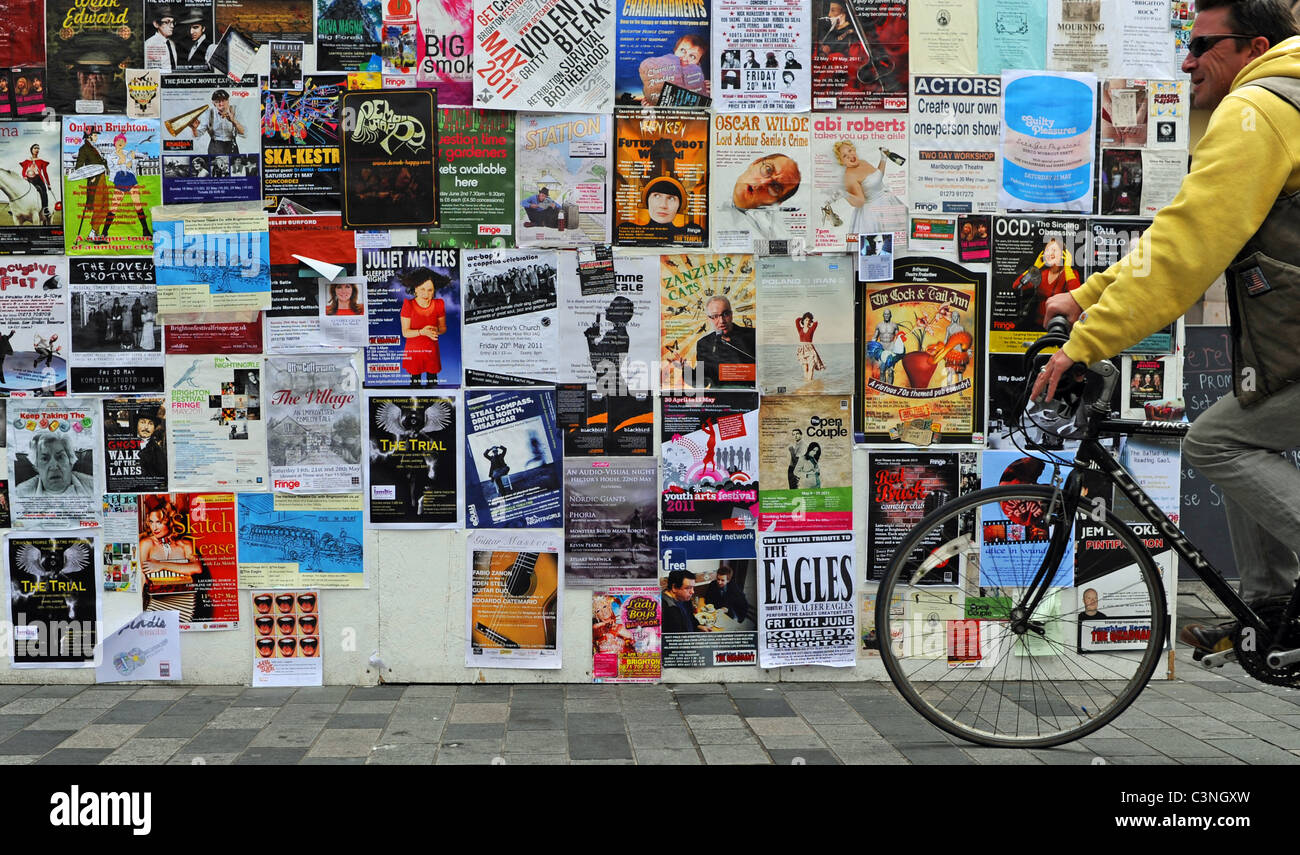 Vorbei an den Flyern des Brighton Festivals an einer Mauer im Stadtzentrum von Großbritannien Stockfoto