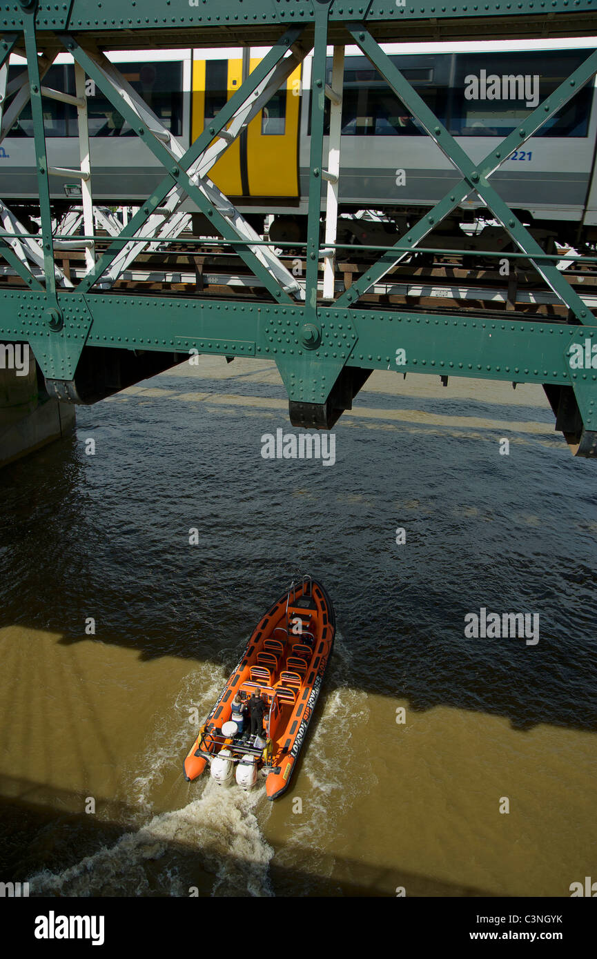 Motorboot auf Themse Unterquerung der Eisenbahnbrücke mit dem Zug. Stockfoto