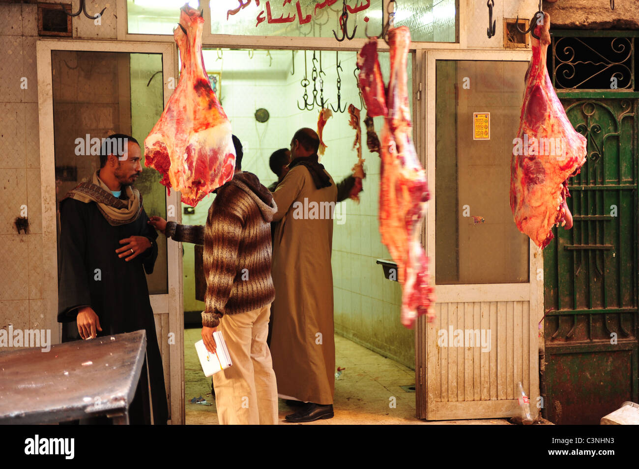 Afrika Ägypten ägyptischen Luxor El Souk Markt im Nahen Osten Gasse einkaufen und Essen - Männer in einer Metzgerei mit Fleisch hängen Stockfoto