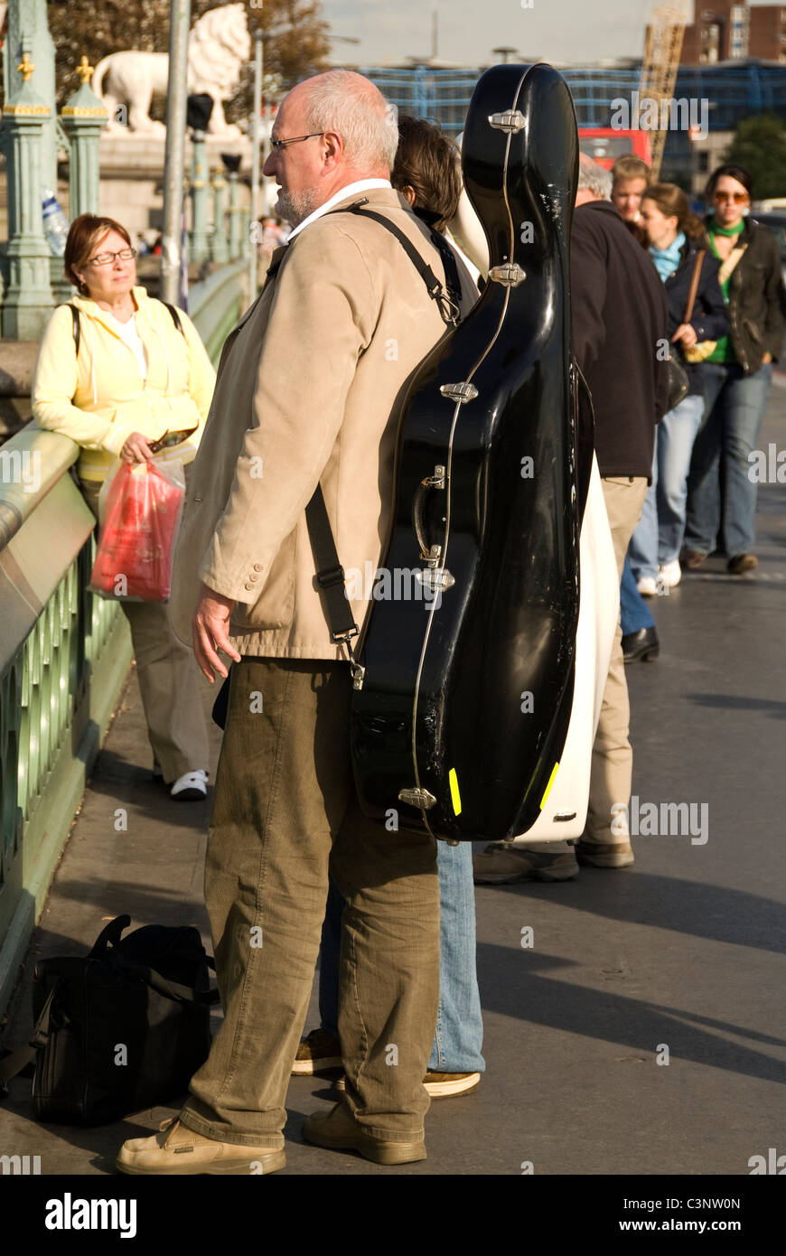 Cellist mit einem Cellokasten auf seinem Rücken, Westminster Bridge, London, England, UK Stockfoto
