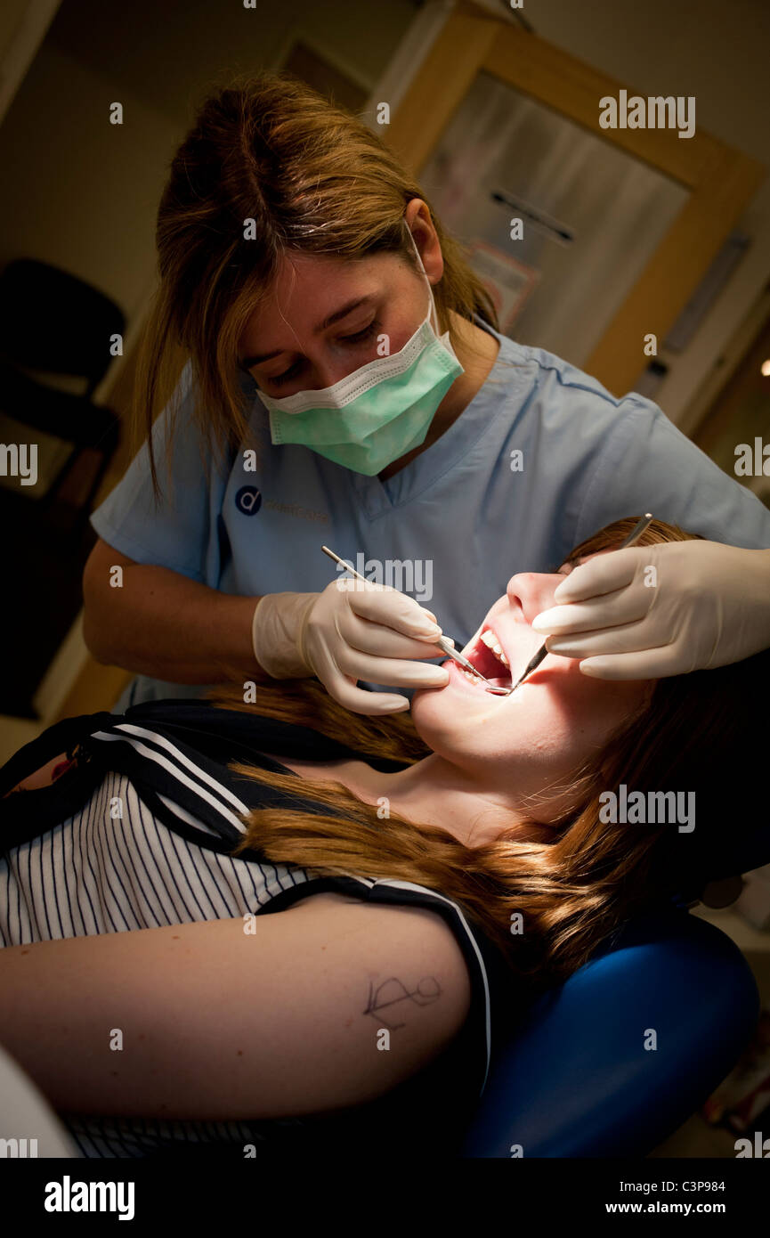 ein junges Mädchen bekommen ihre Zähne überprüft von einer Frau NHS Zahnarzt, UK Stockfoto