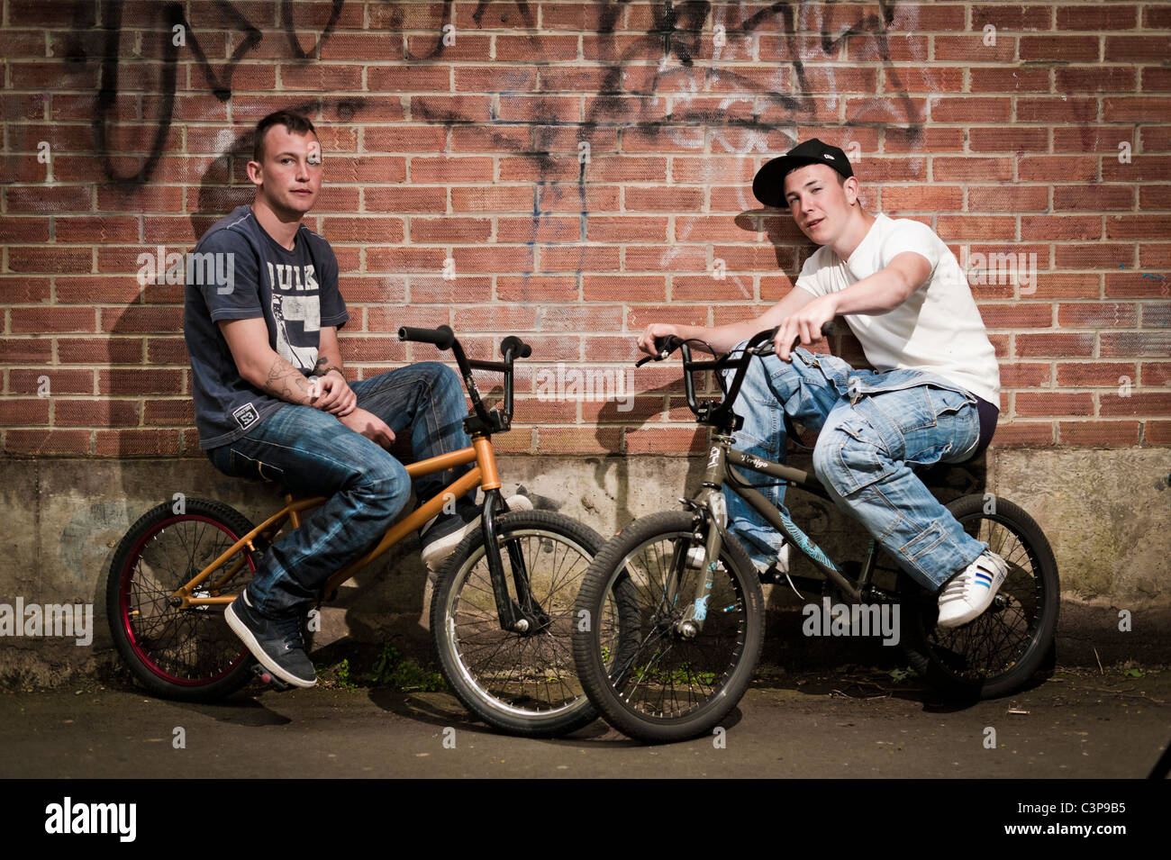 Zwei jungen im Teenageralter mit Einstellung auf BMX Stunt Bikes gelehnt eine Mauer, UK Stockfoto