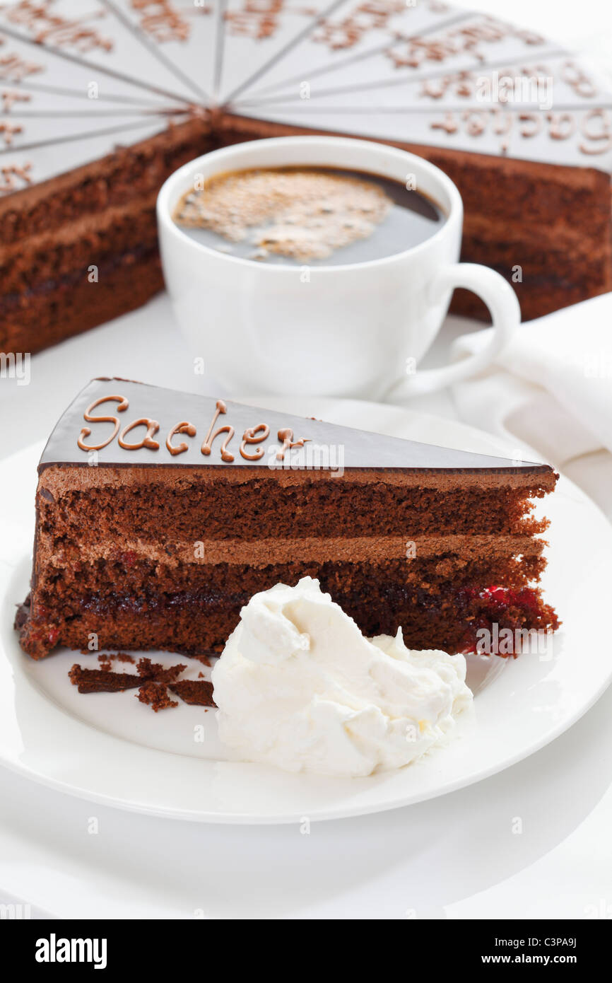 Nahaufnahme von Sacher Torte Slice und Schlagsahne im Teller mit Kaffeetasse  Stockfotografie - Alamy
