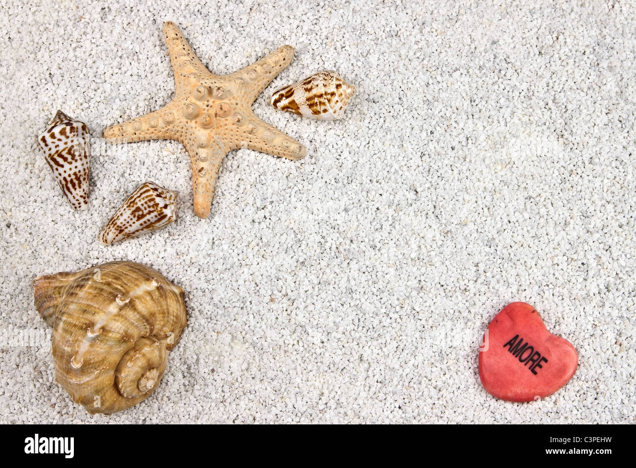 ein Seastar und mehrere Muscheln im weißen Sand mit Herz Stockfoto