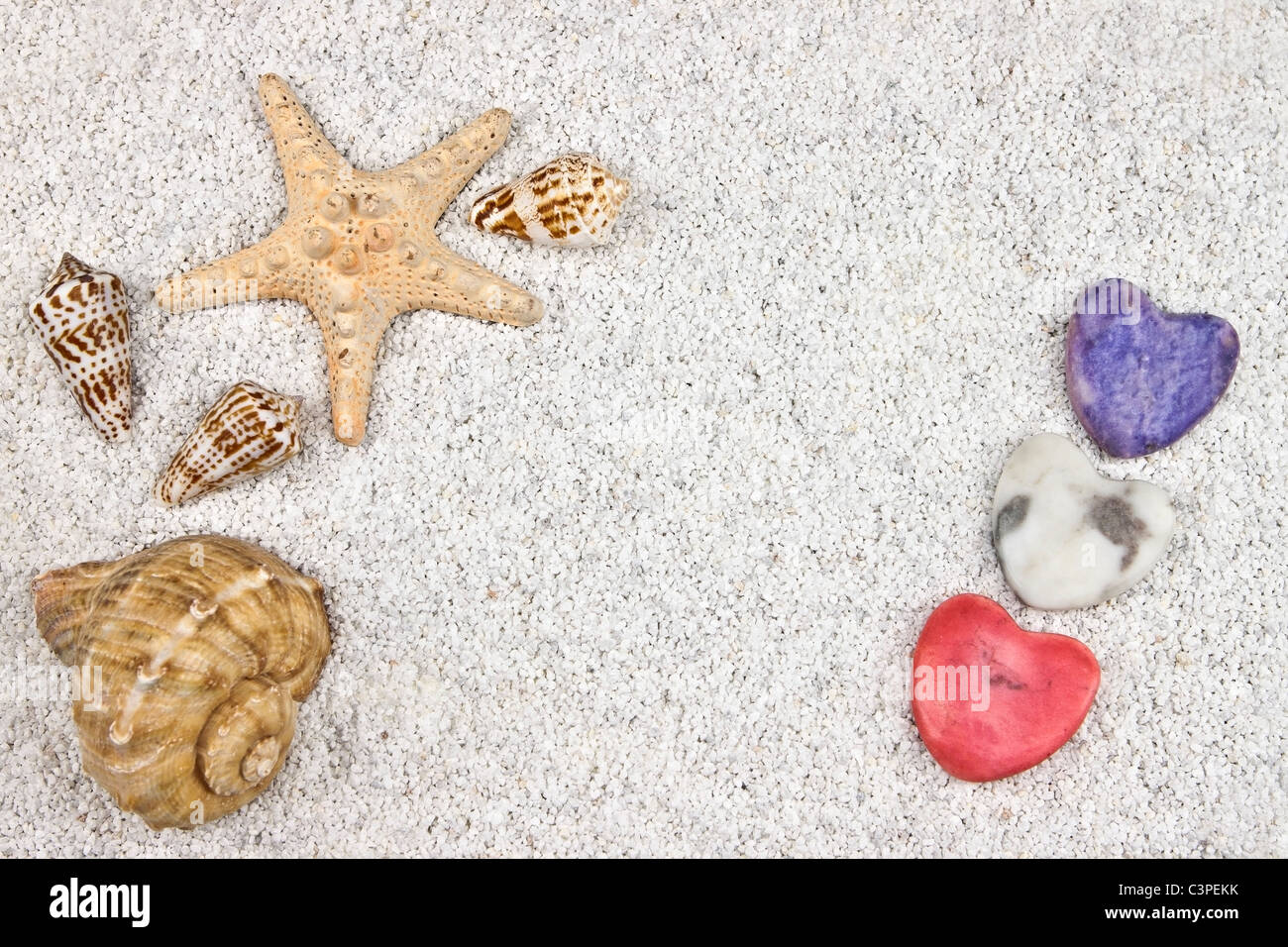 ein Seastar und mehrere Muscheln im weißen Sand mit drei Herzen Stockfoto