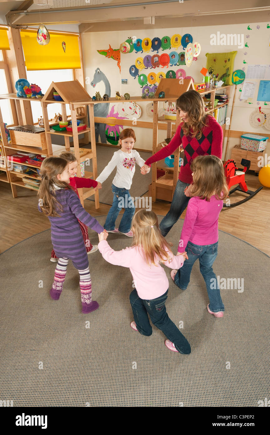 Deutschland, Kindergarten, weibliche Kindergärtnerin und Kinder tanzen Stockfoto