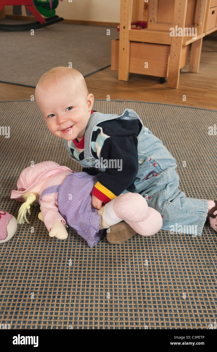 Deutschland, Babymädchen (12-17 Monate) im Kindergarten, das Spiel mit Puppen, Lächeln, Porträt Stockfoto