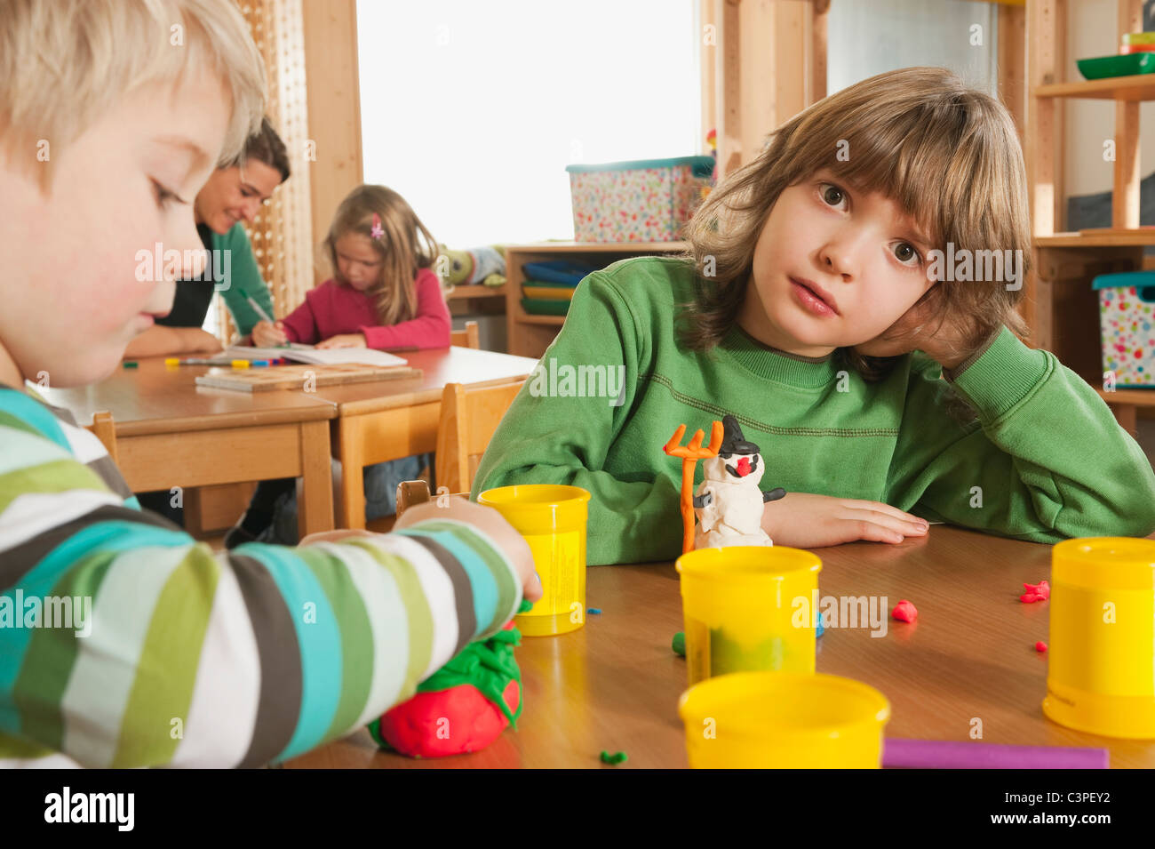 Deutschland, Kinder Kindergarten, weibliche Kindergärtnerin im Hintergrund Stockfoto