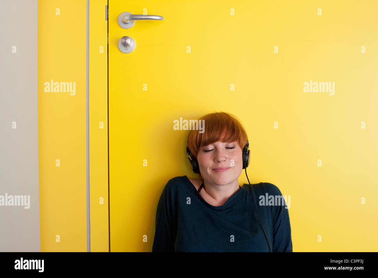 Deutschland, Leipzig, junge Frau sitzen und hören Sie Musik in Umkleidekabine Stockfoto